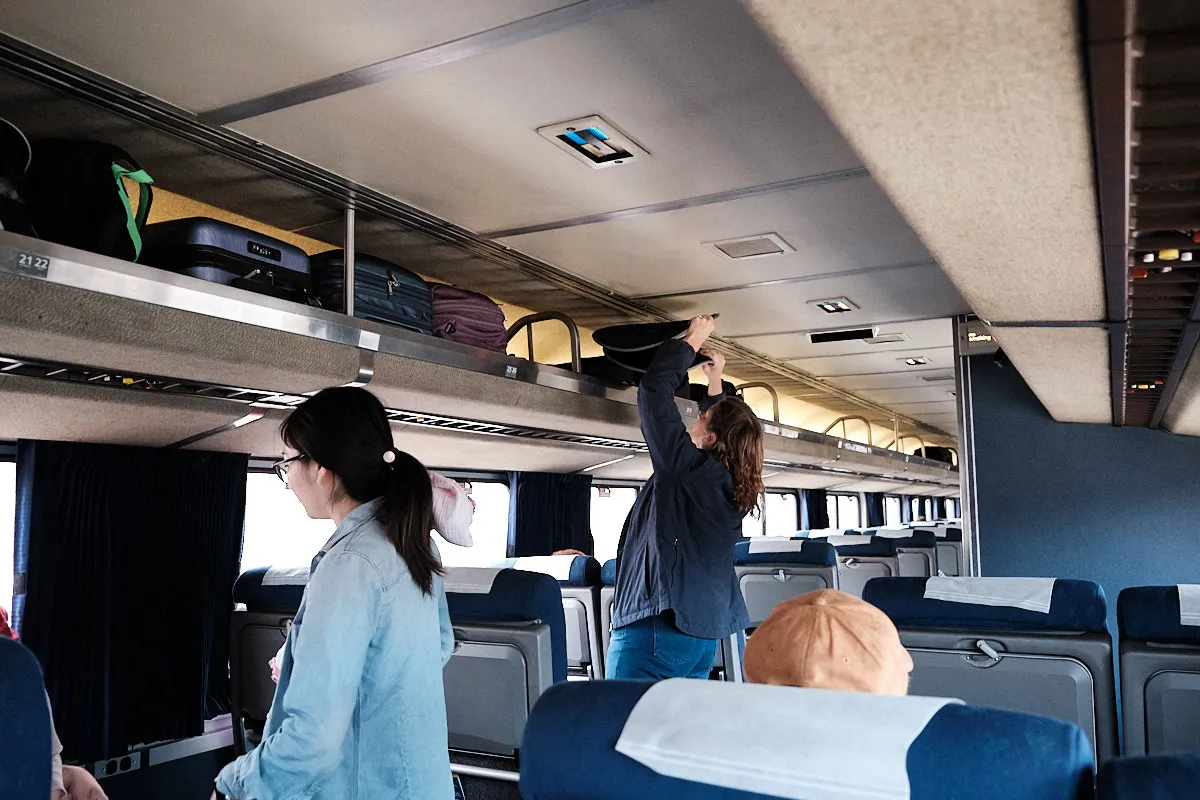 Someone packing luggage in the overhad rack on Amtrak's Southwest Chief train