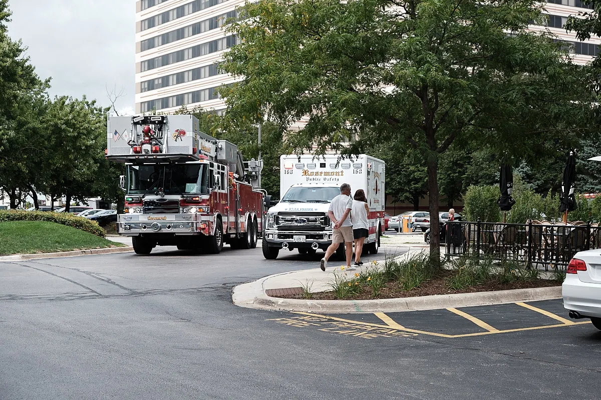 Standing in the hotel parking lot. A fire truck and an ambulance are parked in the middle of the road.