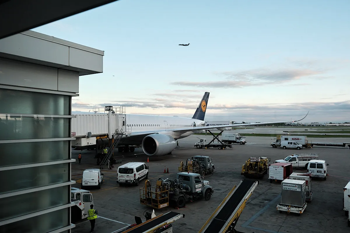 Looking out the window at our gate, we see our Iceland Air plane. There are lots of ground vehicles nearby, and a plane taking off in the background.